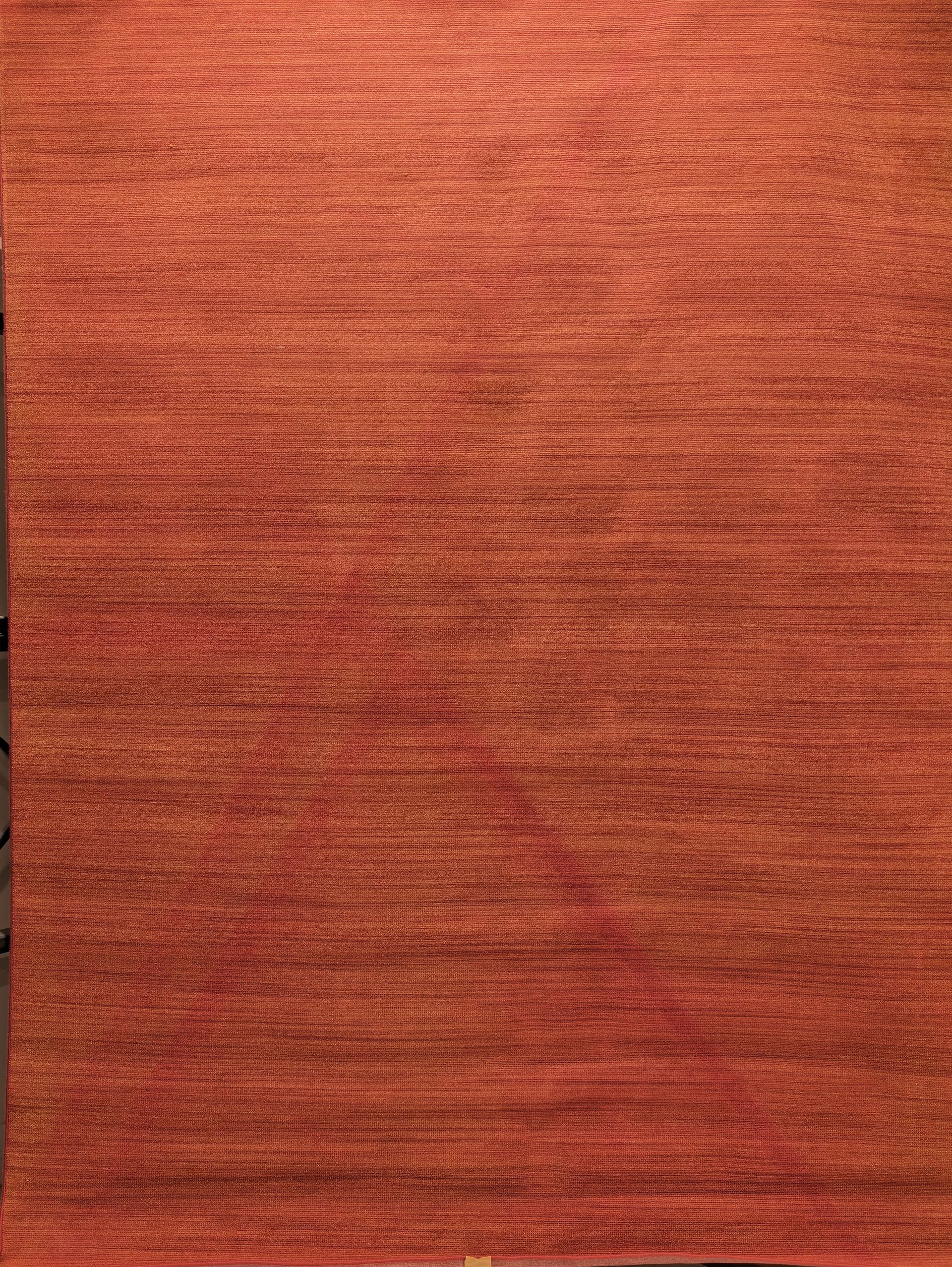 Close-up of a reddish-orange textured fabric with wavy horizontal patterns