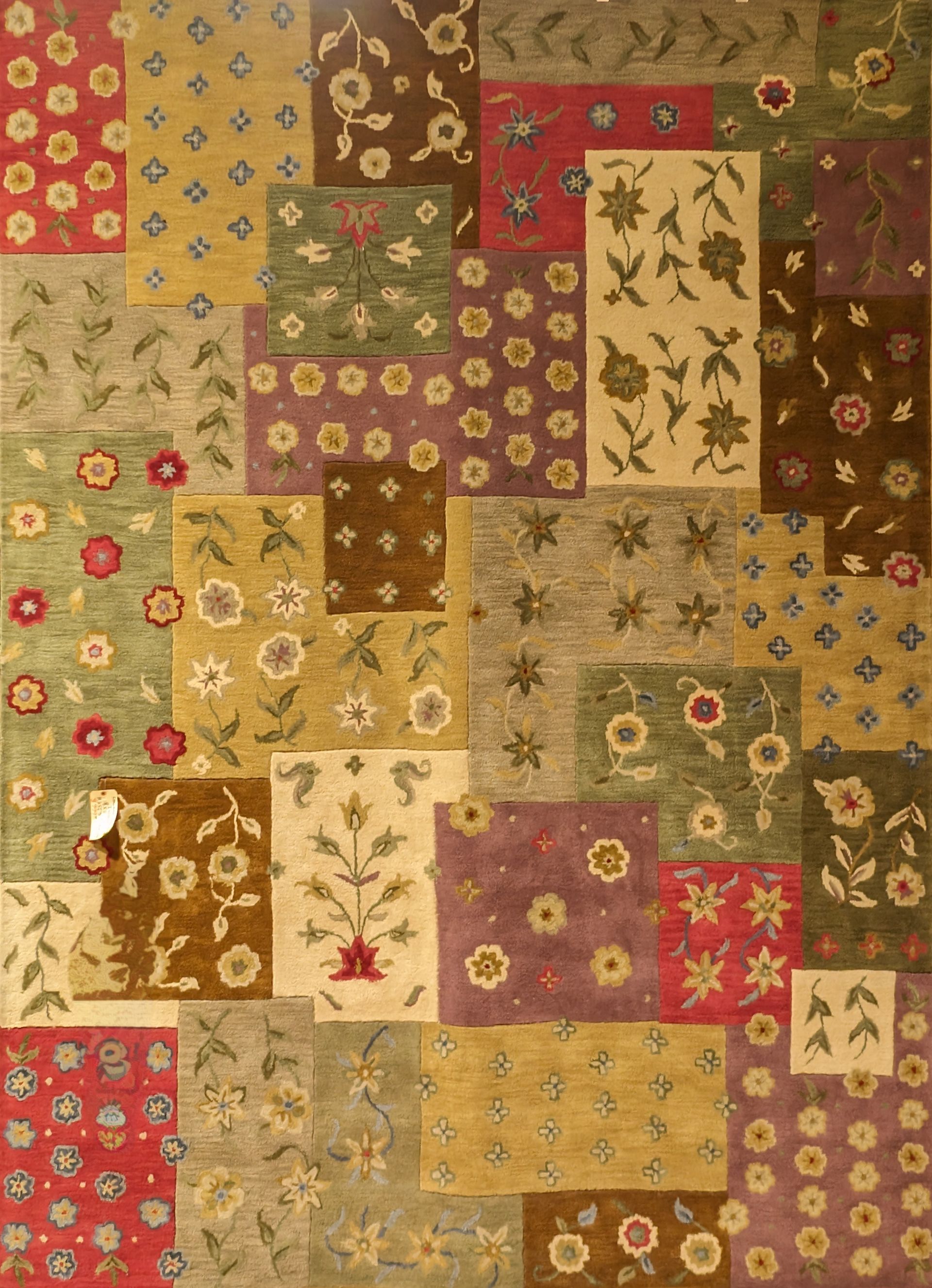 Patchwork quilt of floral fabric squares in warm reds, greens, golds, and beige, with leaf and flower motifs