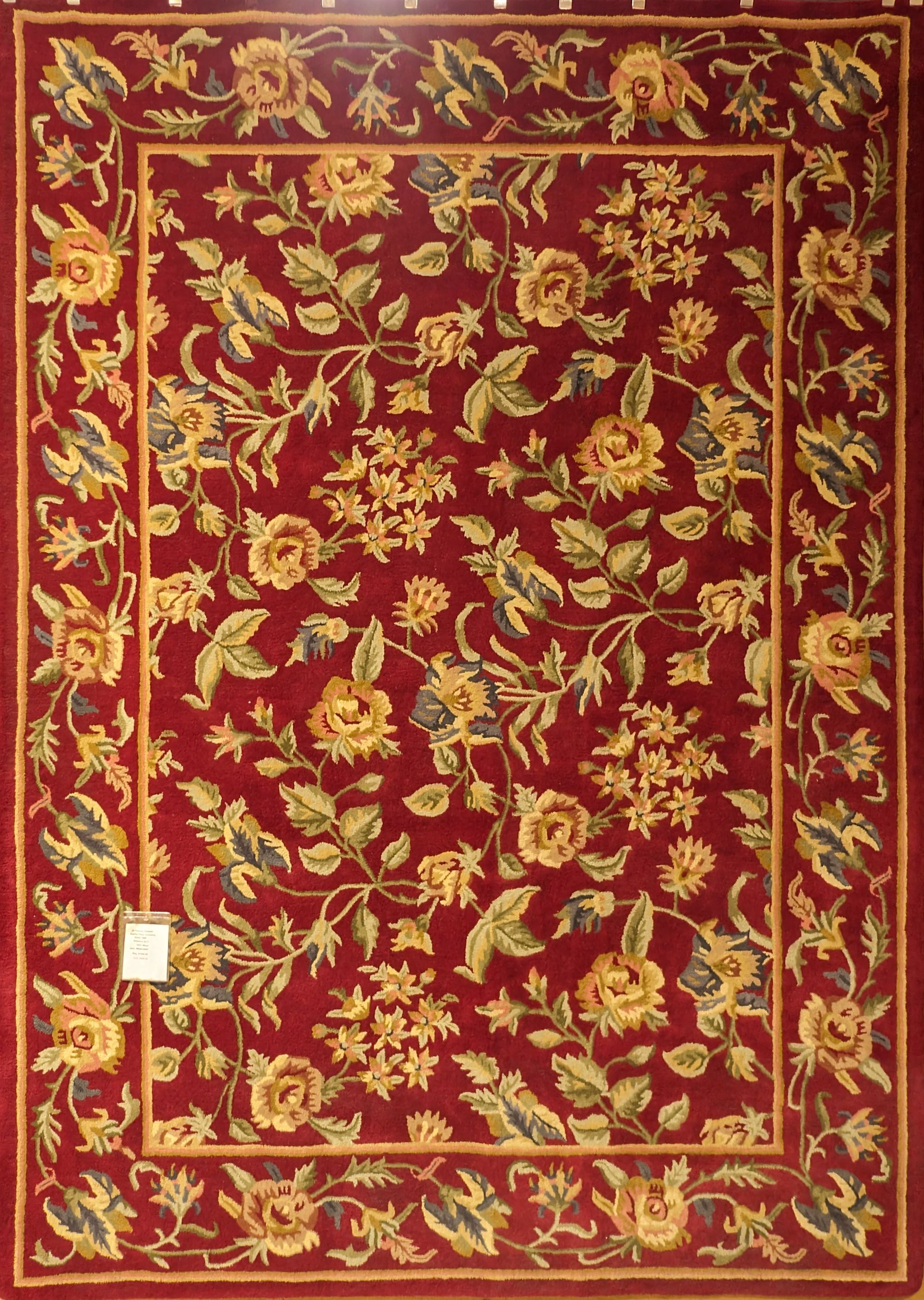 Red floral tapestry or rug with ornate gold border on a burgundy background