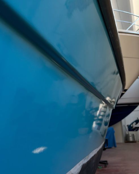 Primo piano dello scafo di una barca blu con una striscia nera, all'interno di uno showroom.