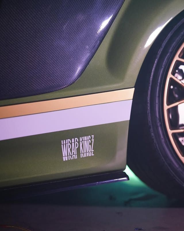 Primo piano di una minigonna laterale verde per auto sportiva con striscia e cerchione viola, che mostra un adesivo WRAP N RIDE.