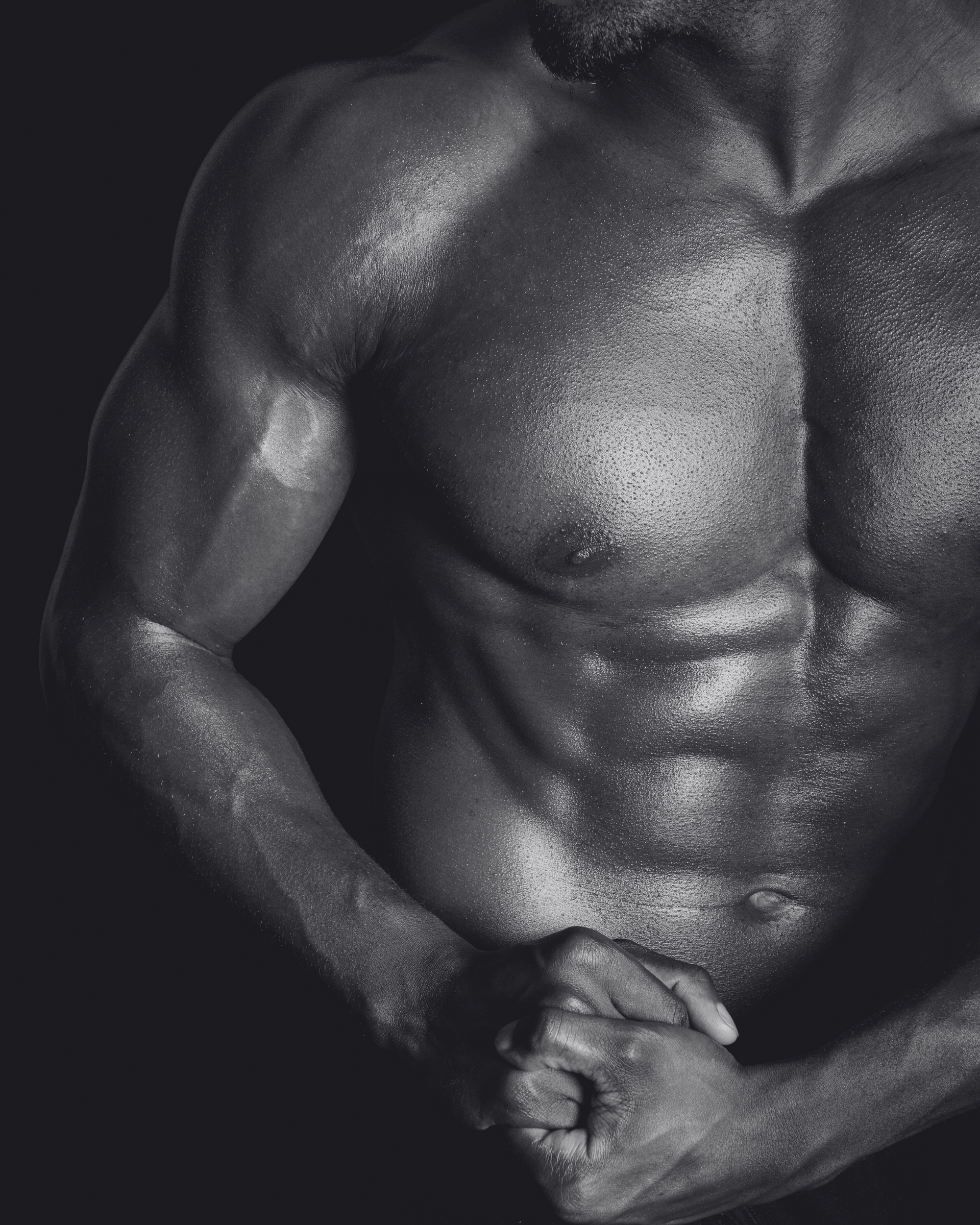 A man without a shirt is flexing his muscles in a black and white photo.