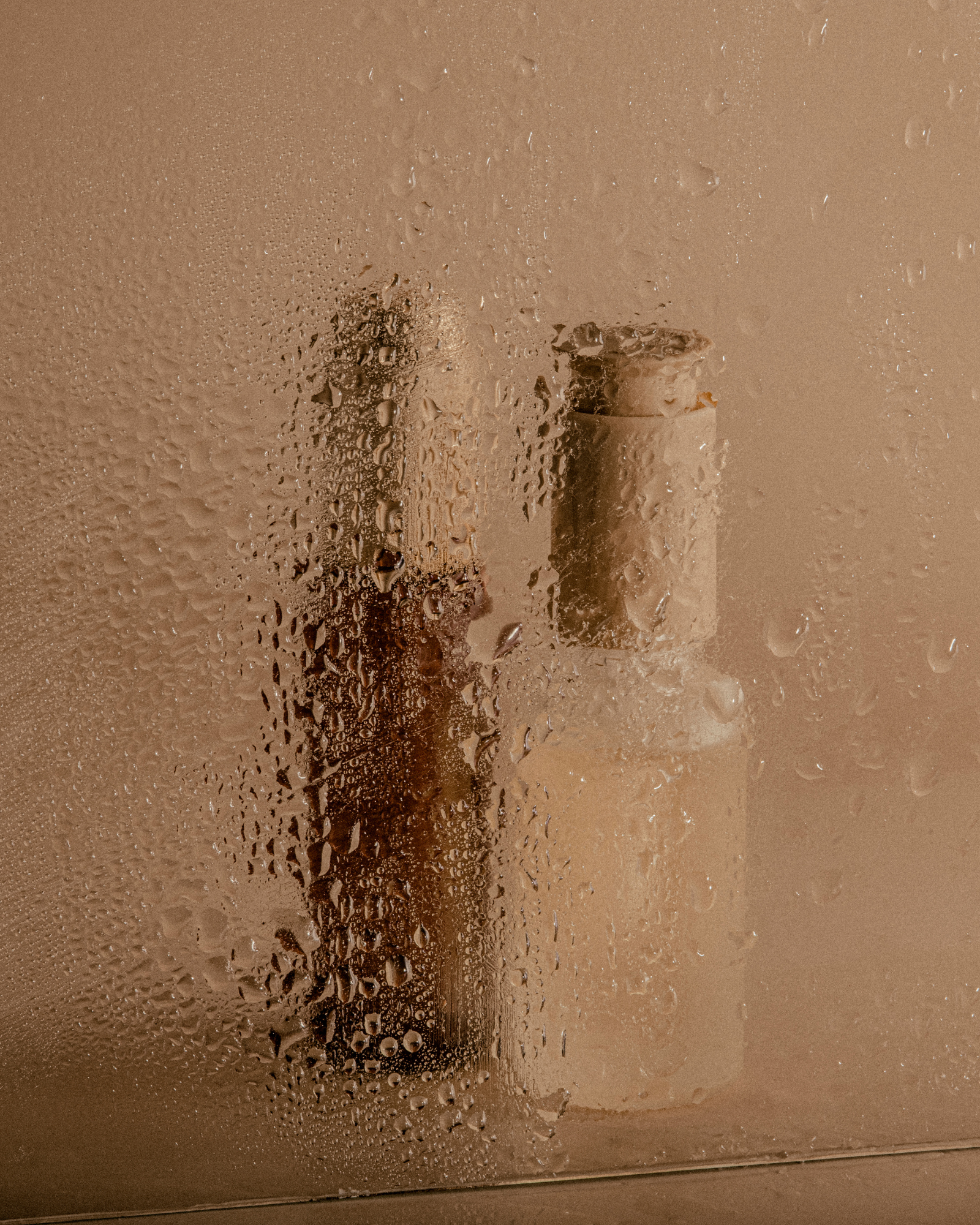Two bottles of liquid are sitting on a glass table.
