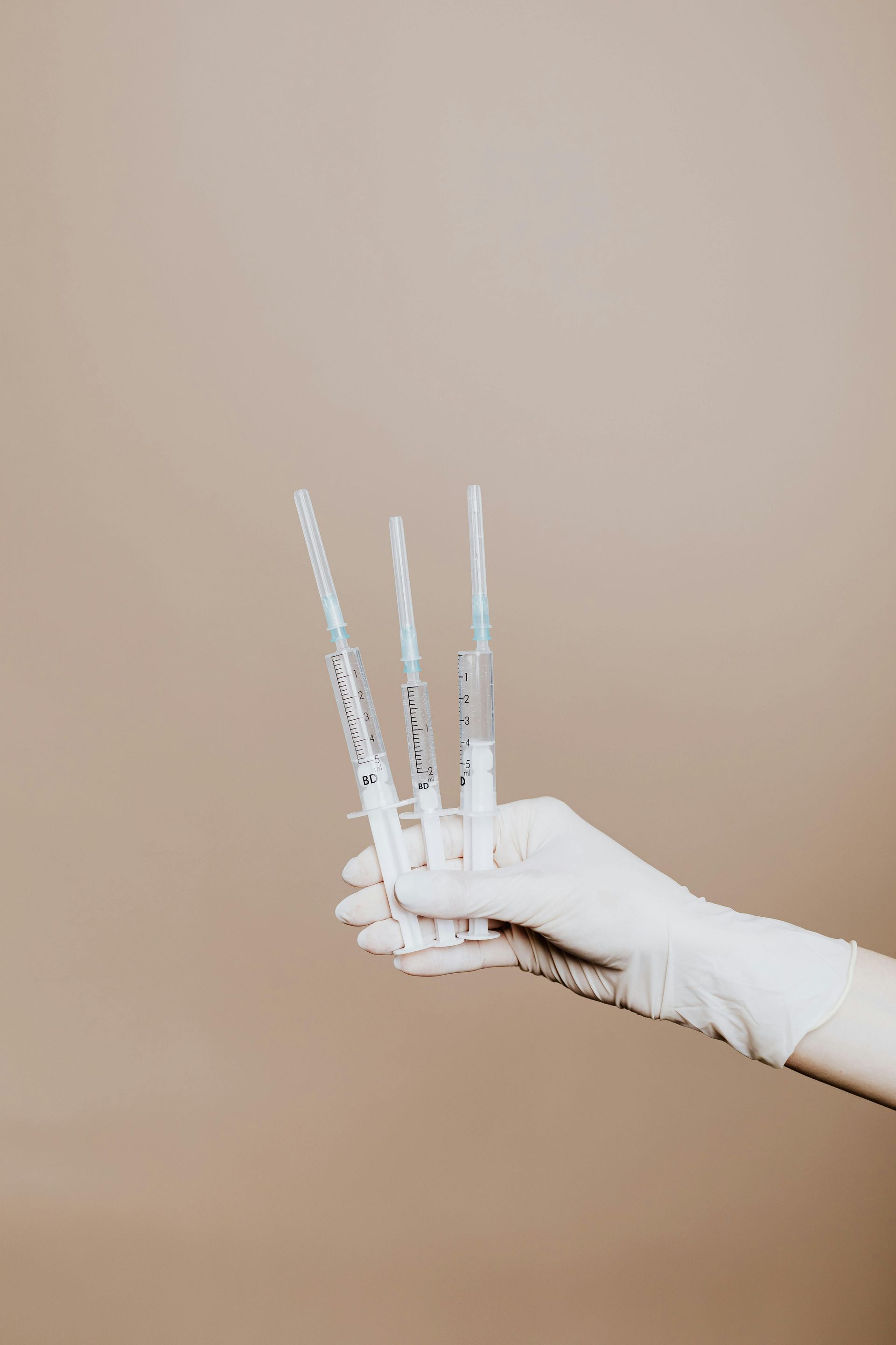 A person is holding three syringes in their hands.