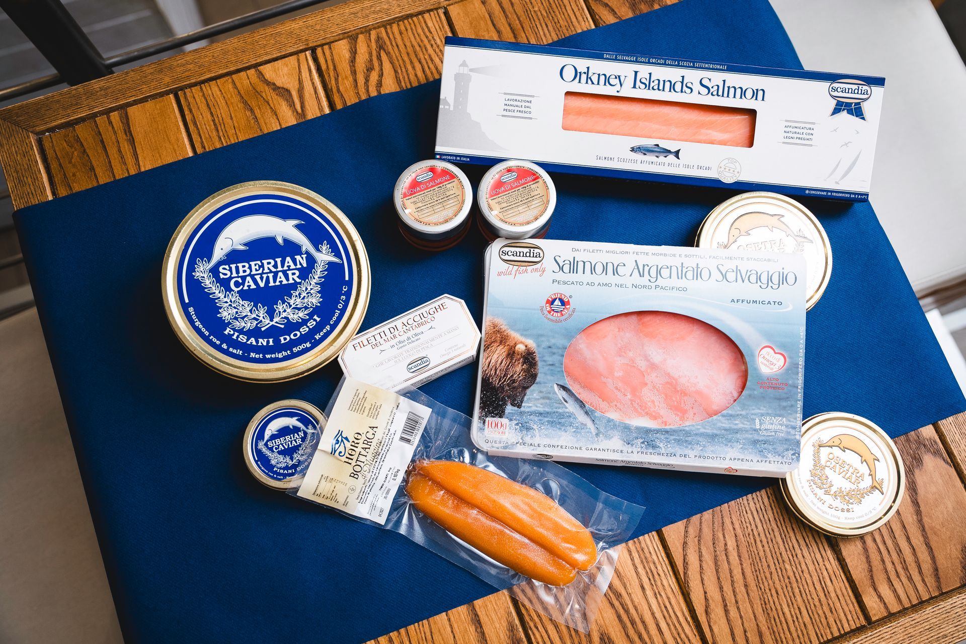 Salmone affumicato assortito e prodotti ittici in confezioni blu e bianche su un tavolo di legno
