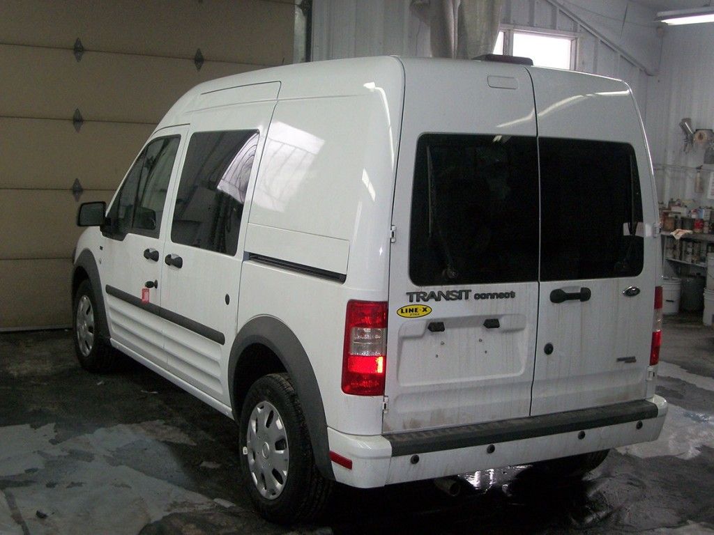 Fourgonnette Ford Transit Connect blanche dans un garage.