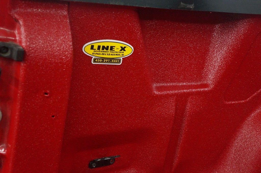 Intérieur de benne rouge avec autocollant logo LINE-X, finition texturée.