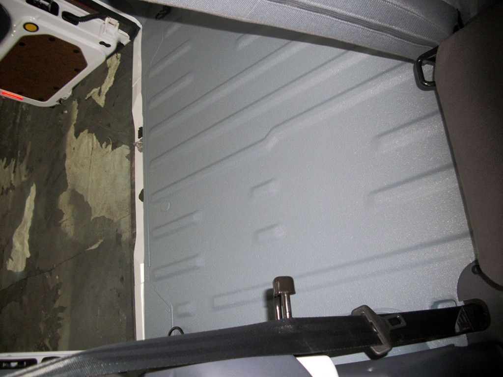 À l'intérieur d'une camionnette à l'intérieur texturé gris clair. Un objet noir aux extrémités métalliques se trouve près du sol.