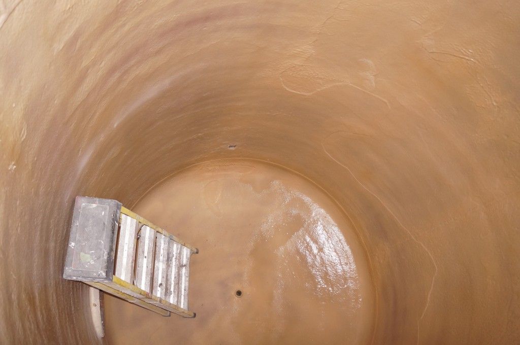 Vue plongeante sur un réservoir cylindrique brun ; une échelle se trouve à l'intérieur.