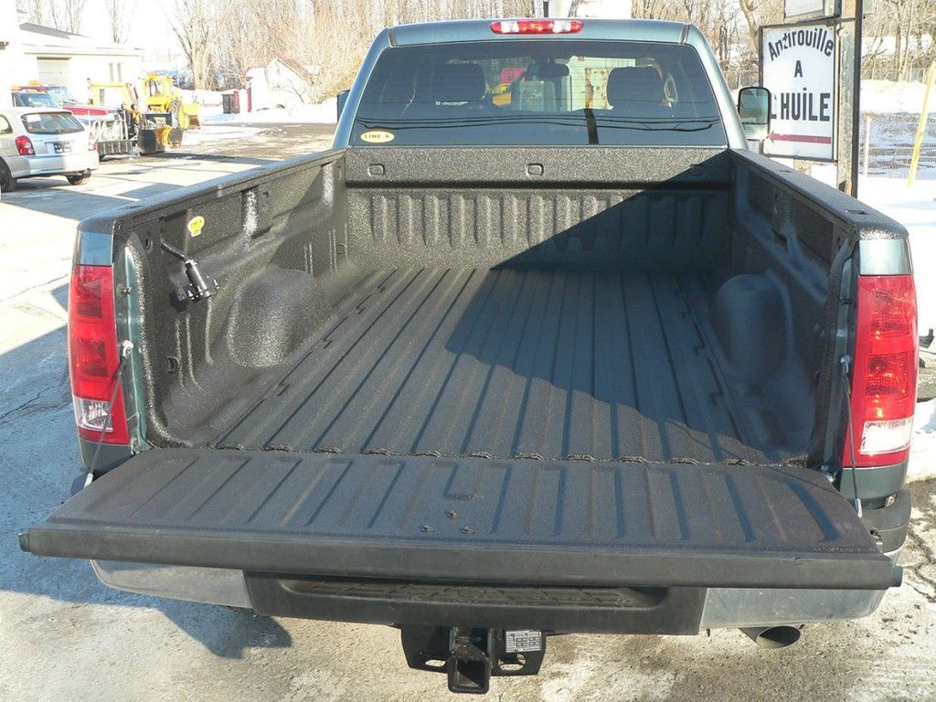 Vue arrière de la benne ouverte d'un pick-up, recouverte d'un revêtement noir, avec le hayon abaissé.