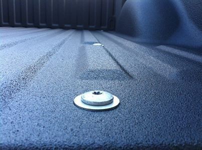 Gros plan sur un revêtement de benne bleu dans un camion avec un anneau d'arrimage métallique.