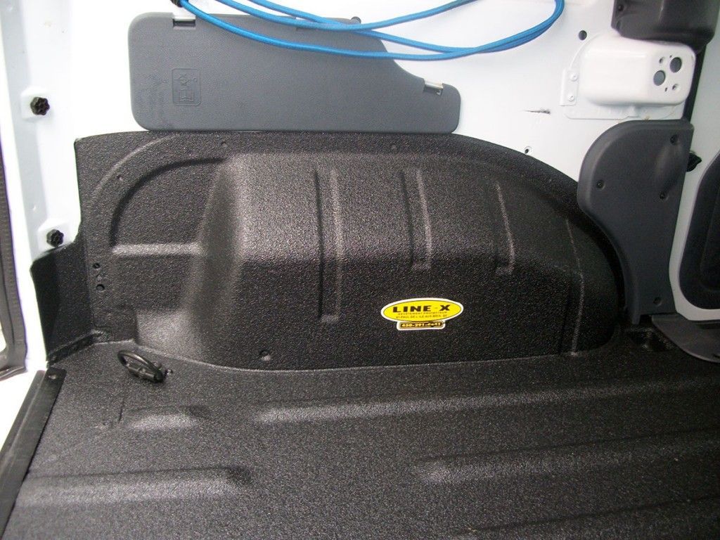 Compartiment de rangement noir à l'intérieur d'une camionnette blanche.