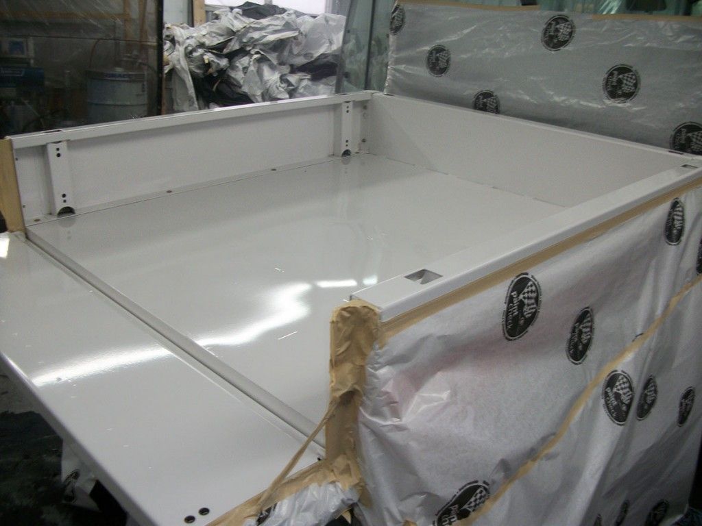 Plateau de camion blanc, fraîchement peint, avec film de protection sur les côtés, à l'intérieur.