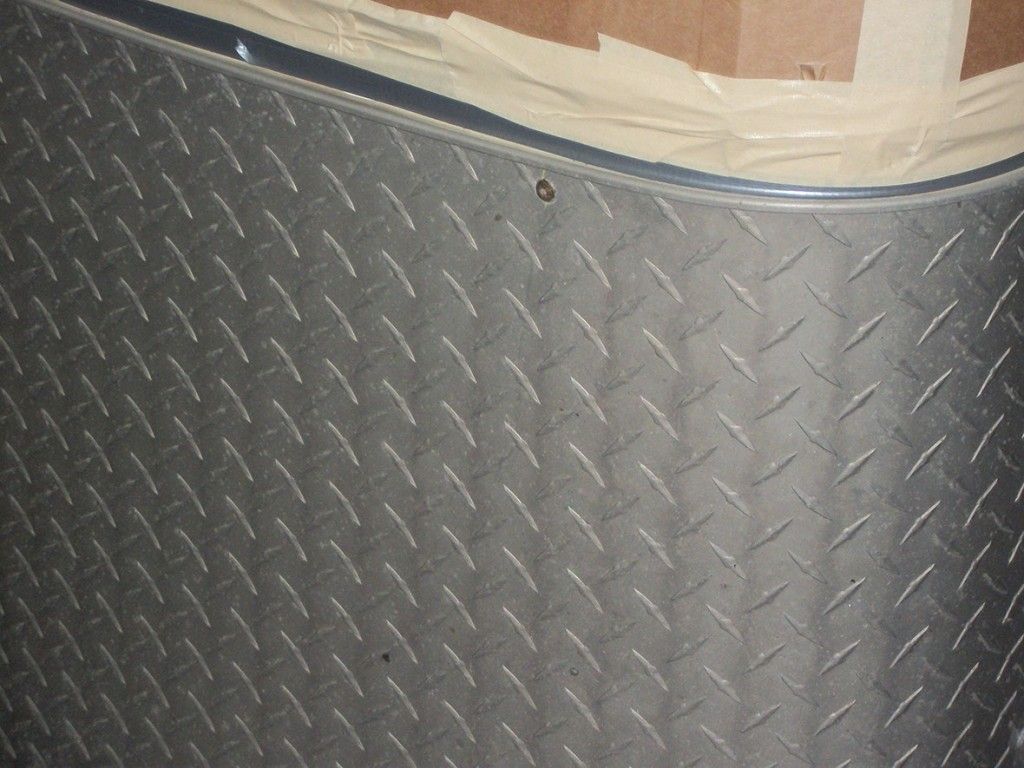 Tôle métallique à damier, incurvée, avec une bordure métallique. Le fond est en bois.