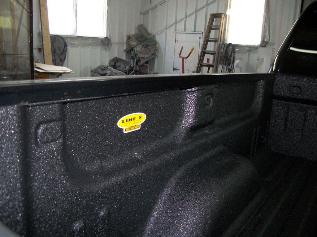 Benne de camion noire avec revêtement de protection Line-X. Arrière-plan d'atelier, vue latérale.