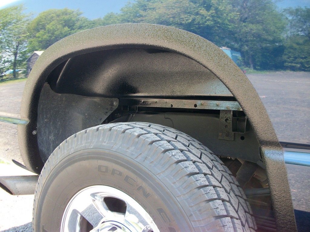 Pneu et passage de roue de camion, recouverts d'un matériau protecteur noir, en extérieur.