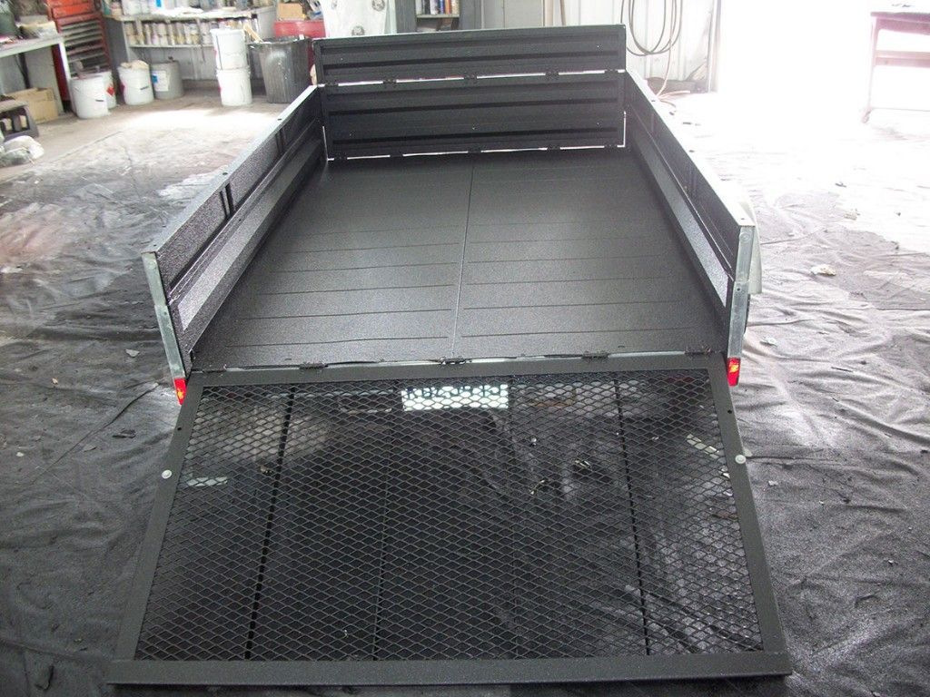 Remorque utilitaire noire avec rampe ouverte, à l'intérieur d'un garage.