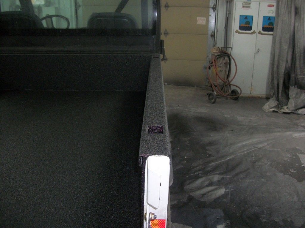 Plateau de camion en tôle larmée avec hayon fermé, dans un garage.