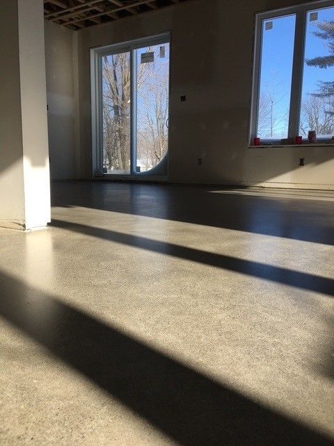 Intérieur baigné de lumière naturelle avec sol en béton poli, fenêtres et colonne blanche.