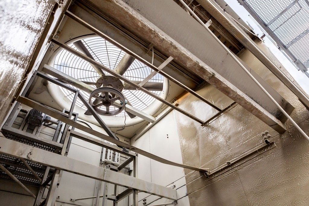 Grand ventilateur industriel monté sur une structure métallique à l'intérieur d'un bâtiment.