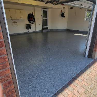 Garage avec un sol en époxy gris moucheté et une porte ouverte.