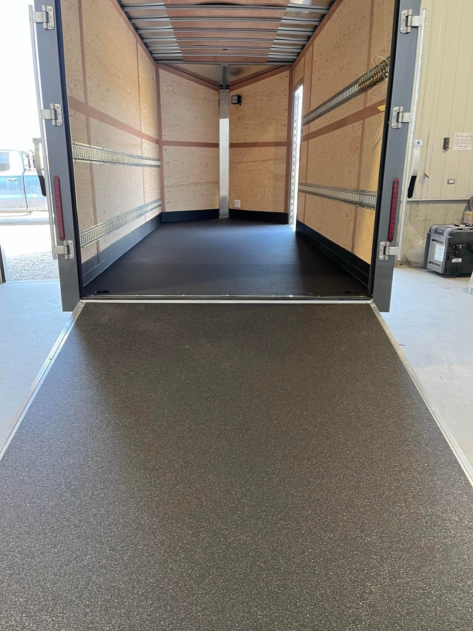 Intérieur vide d'une remorque cargo avec rampe, plancher et panneaux latéraux.