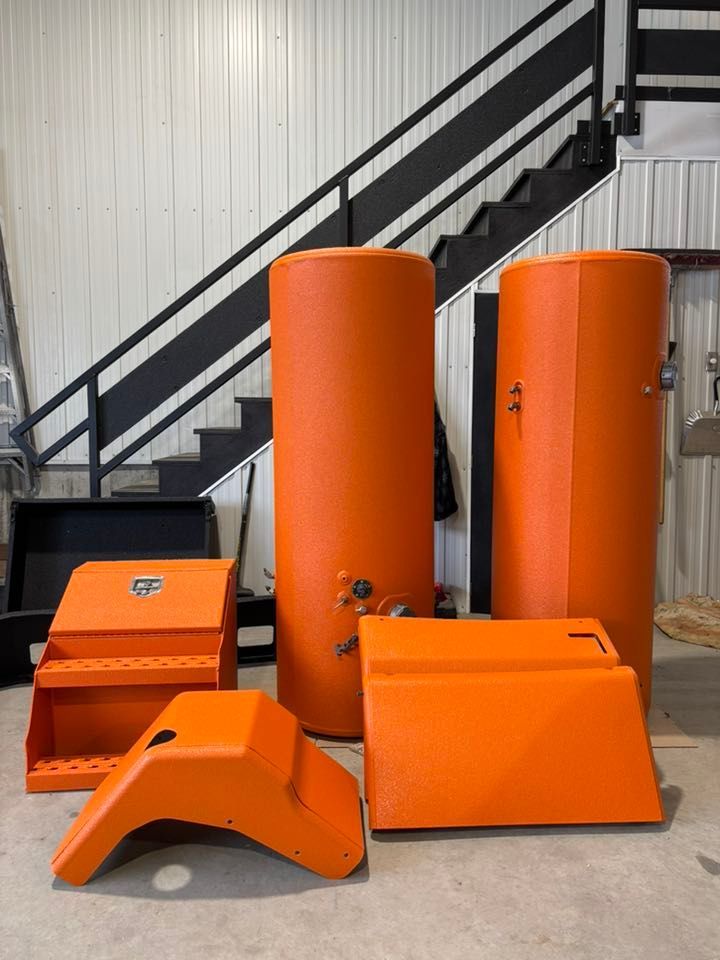 Des pièces industrielles orange et des réservoirs sont mis en scène dans un atelier avec un escalier noir.