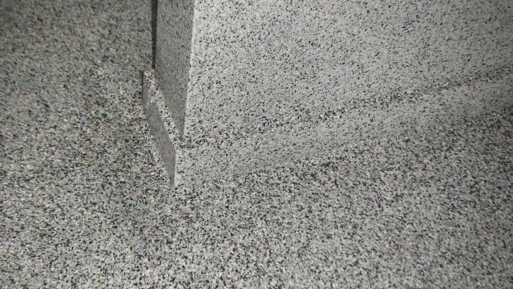 Surface en béton gris moucheté avec un joint vertical.