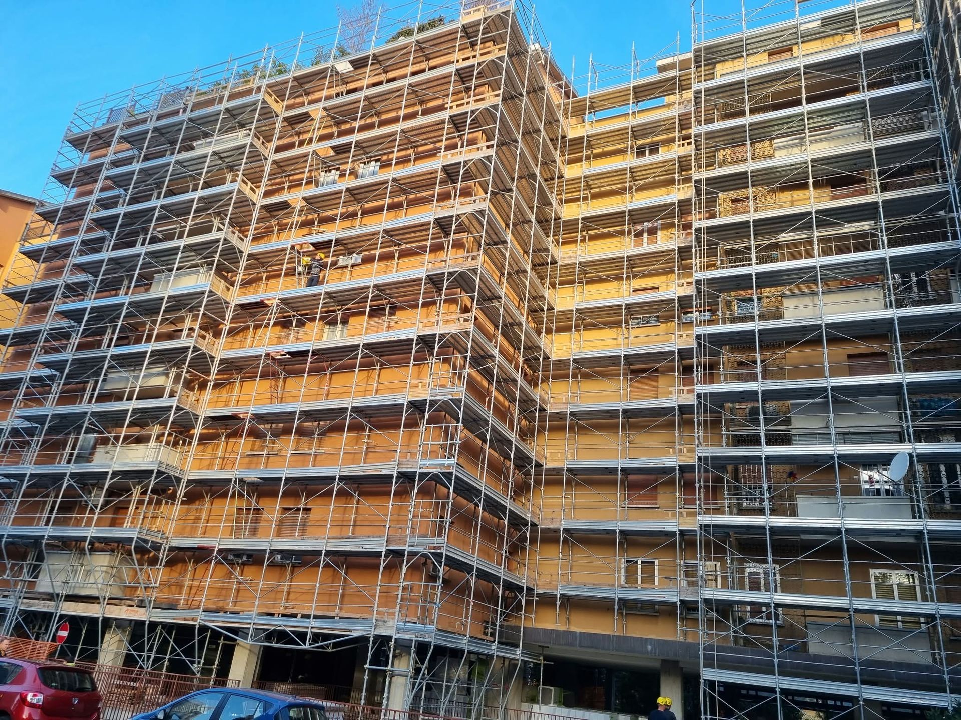 Scaffolded multi-story building under construction against a clear blue sky