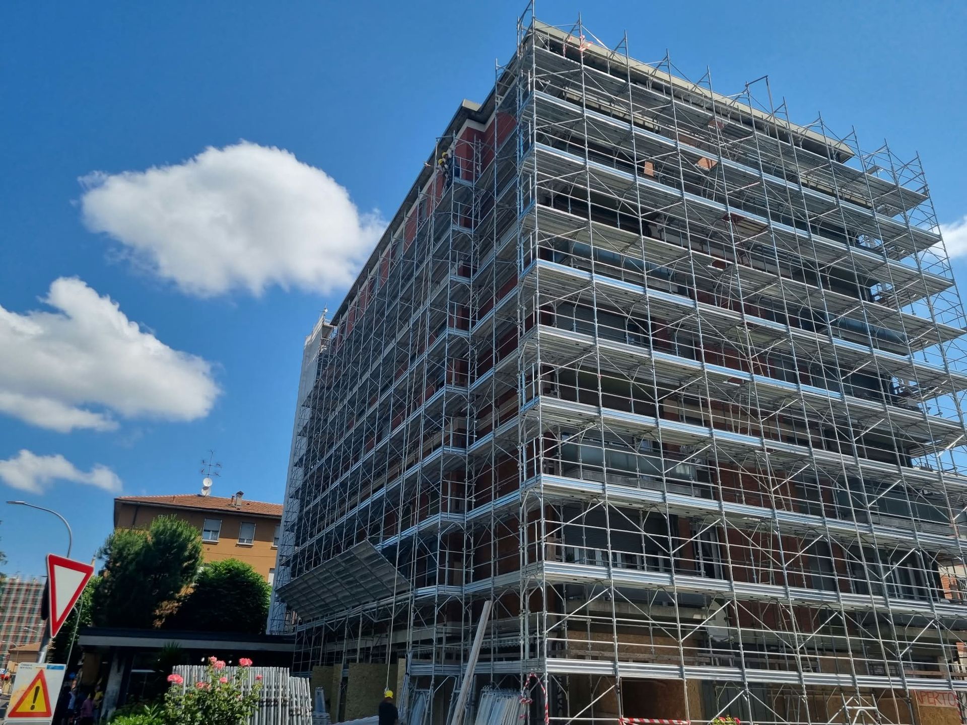 Scaffolded building under construction against a blue sky with clouds