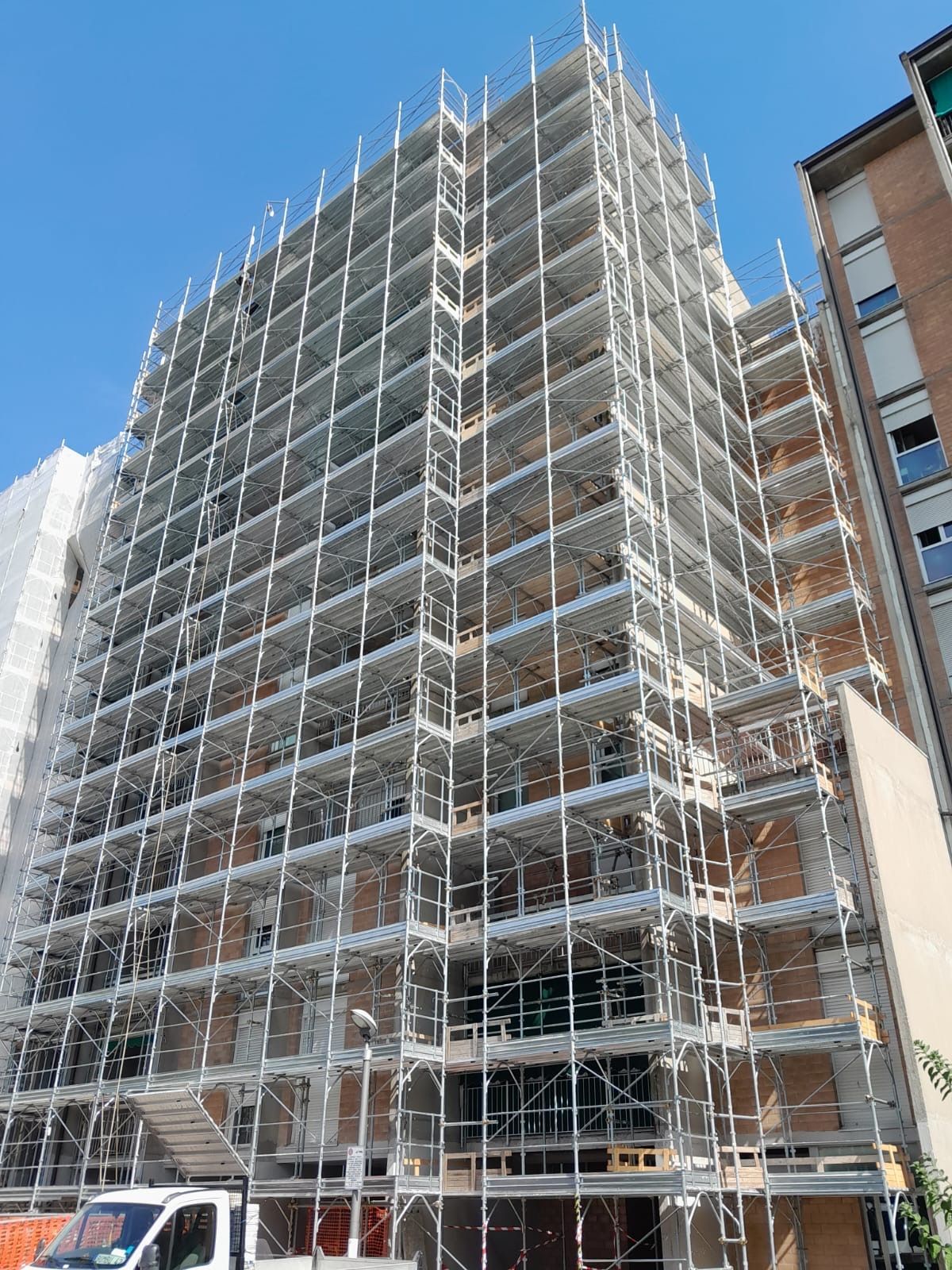 Scaffolded multi-story building under construction against a blue sky