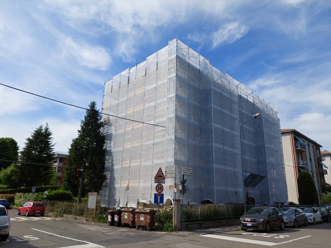 Building wrapped in white scaffolding netting on a street corner under a blue sky