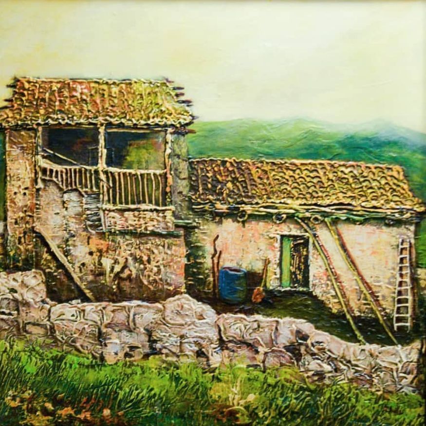 Rustic stone farmhouse with red-tiled roofs and a ladder beside a green field