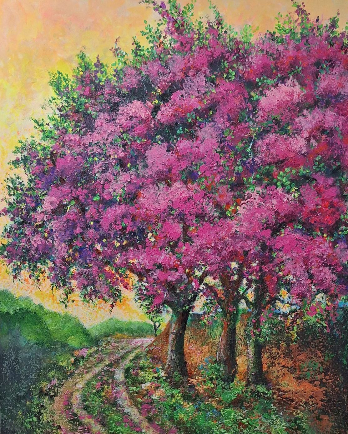 Pink-blossomed tree beside a winding path in a colorful sunset landscape