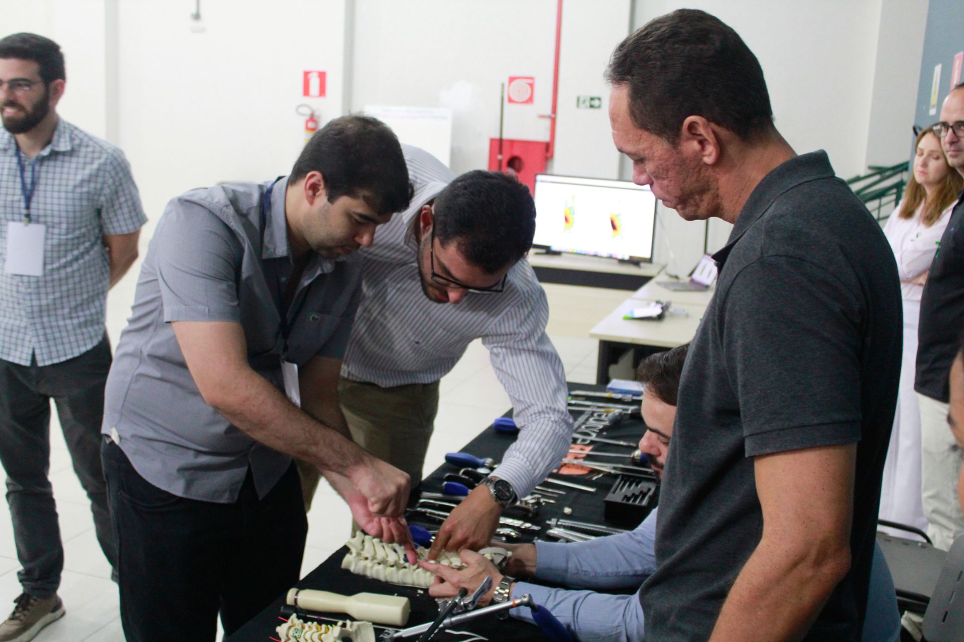 Um grupo de homens está em volta de uma mesa olhando para instrumentos odontológicos.