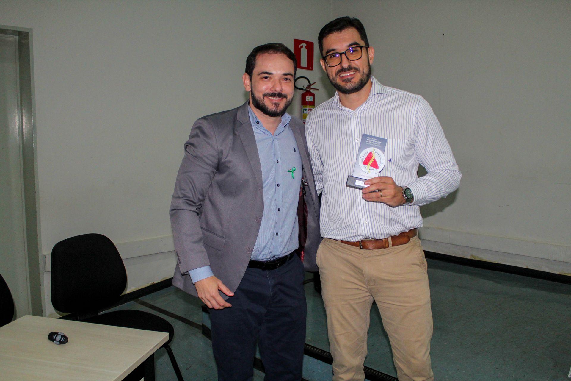 Dois homens estão parados um ao lado do outro em uma sala.
