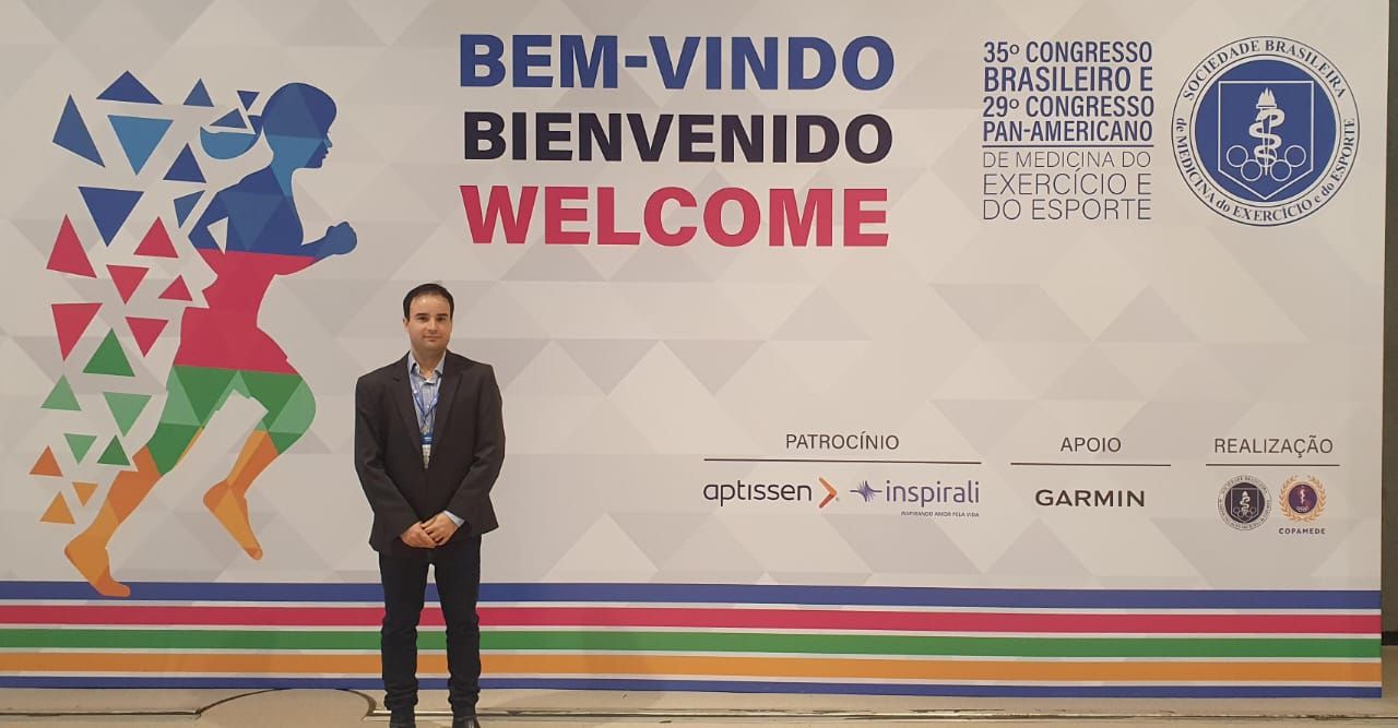 Um homem de terno está parado em frente a uma placa de boas-vindas