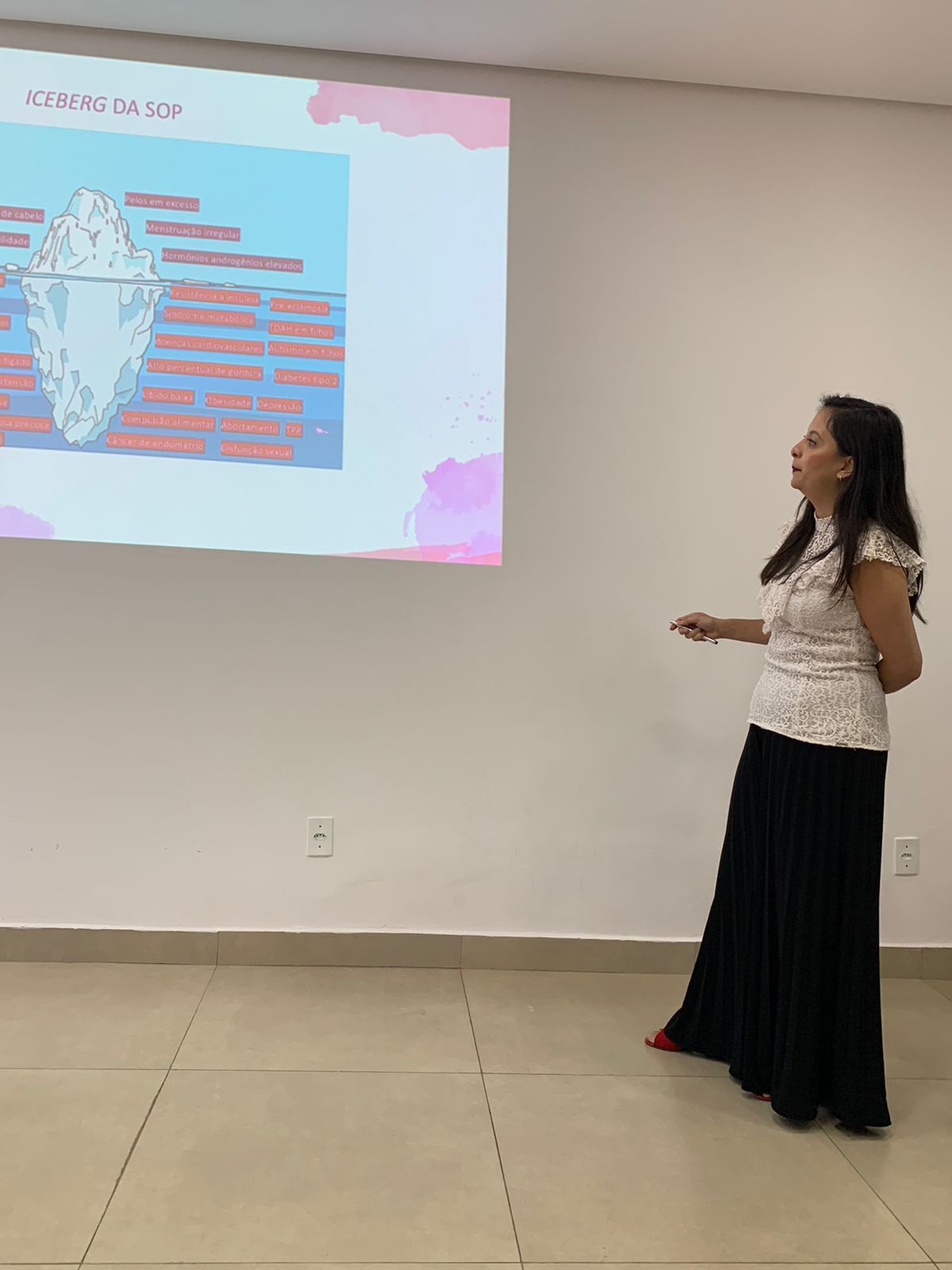 Dra Francine fazendo uma apresentação em frente a uma tela de projetor.