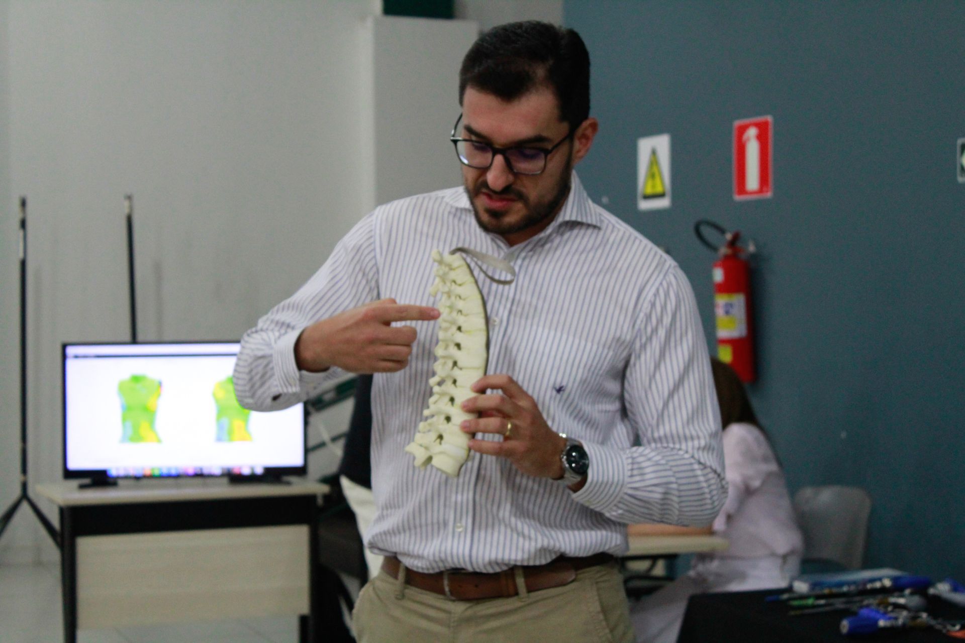 Um homem segura um modelo de coluna vertebral em suas mãos.