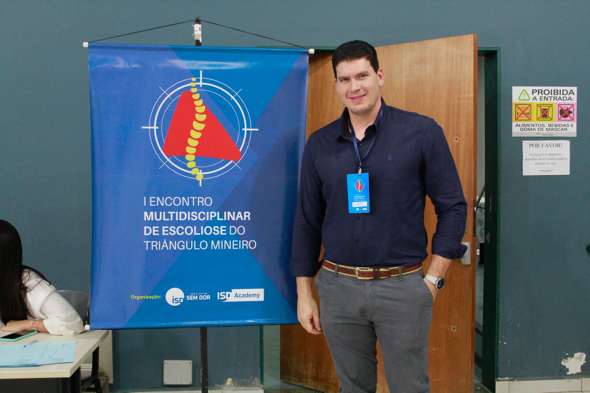 Um homem em pé na frente de uma faixa azul que diz 
