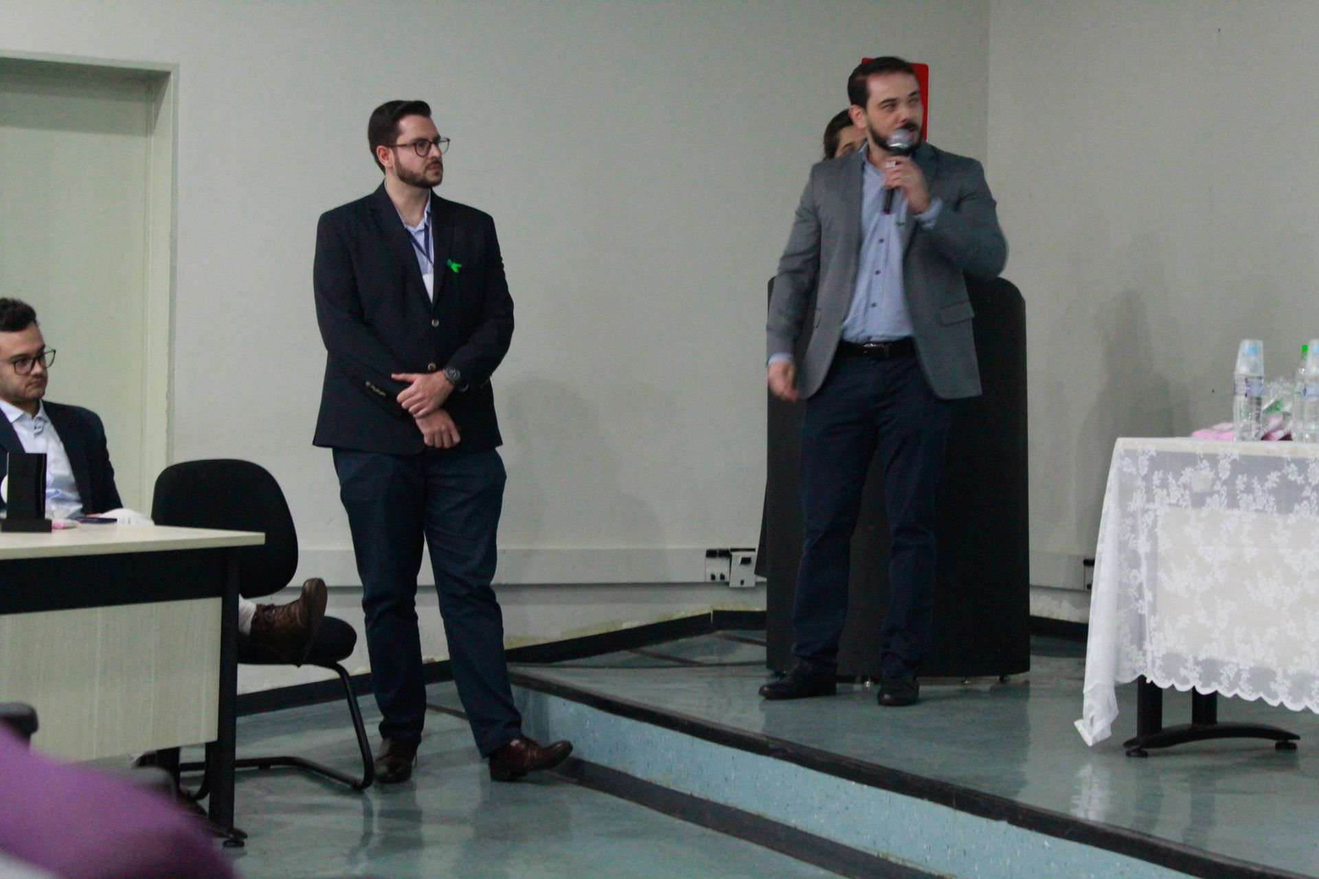 Três homens estão em um palco fazendo uma apresentação.