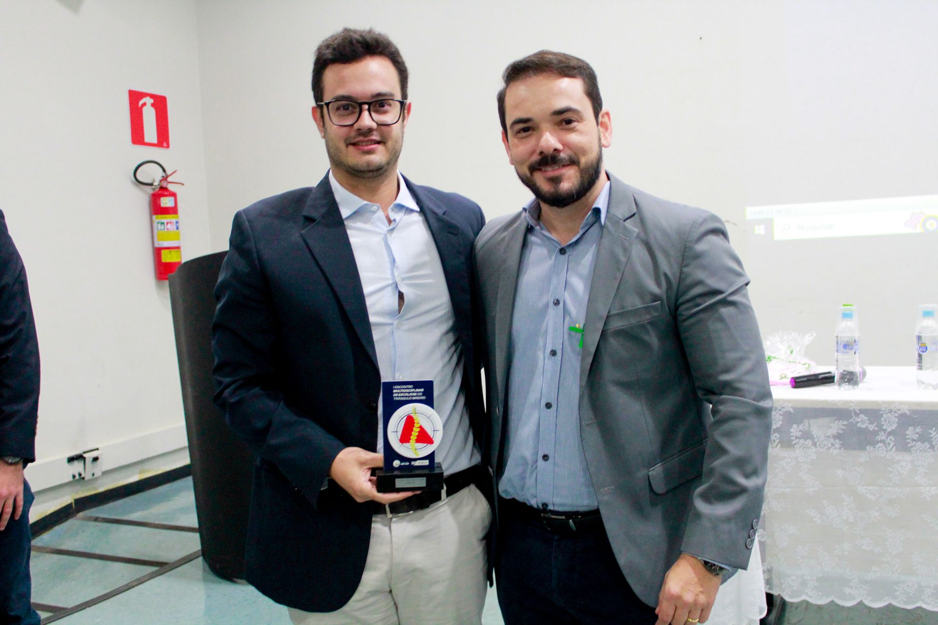 Dois homens estão posando para uma foto enquanto um deles segura uma placa.