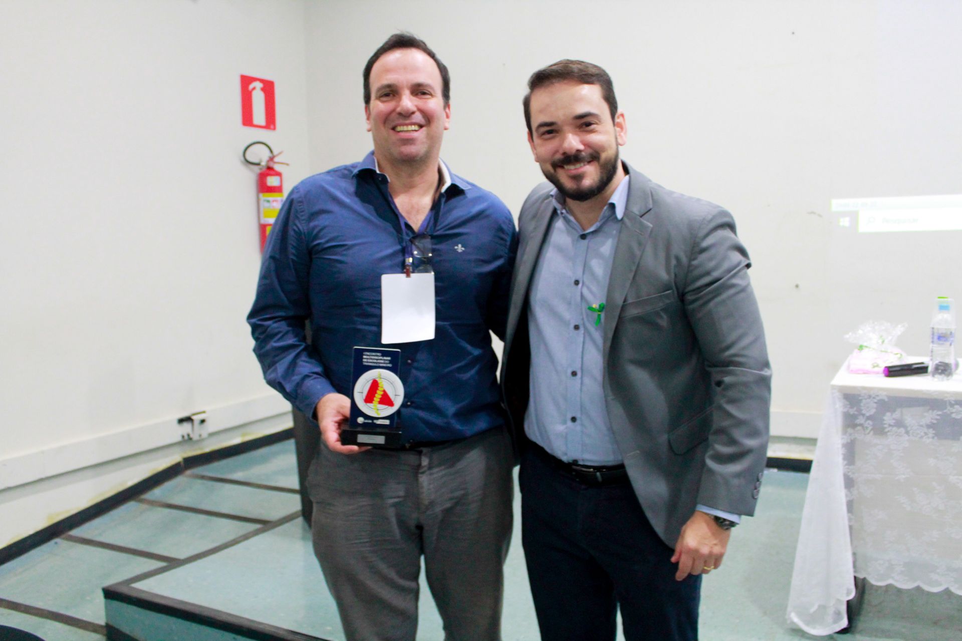 Dois homens estão posando para uma foto juntos em uma sala.
