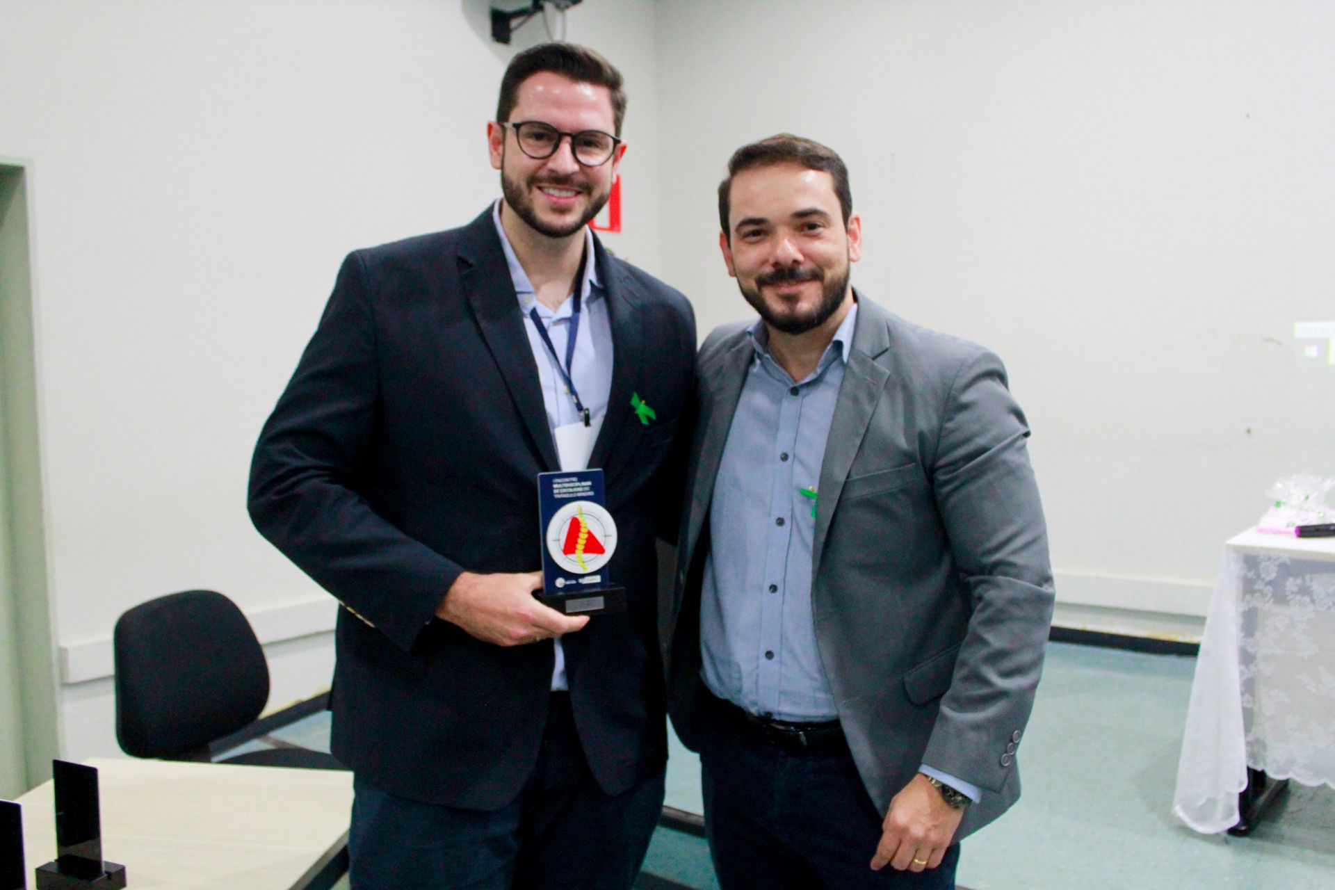 Dois homens de terno estão parados um ao lado do outro em uma sala.