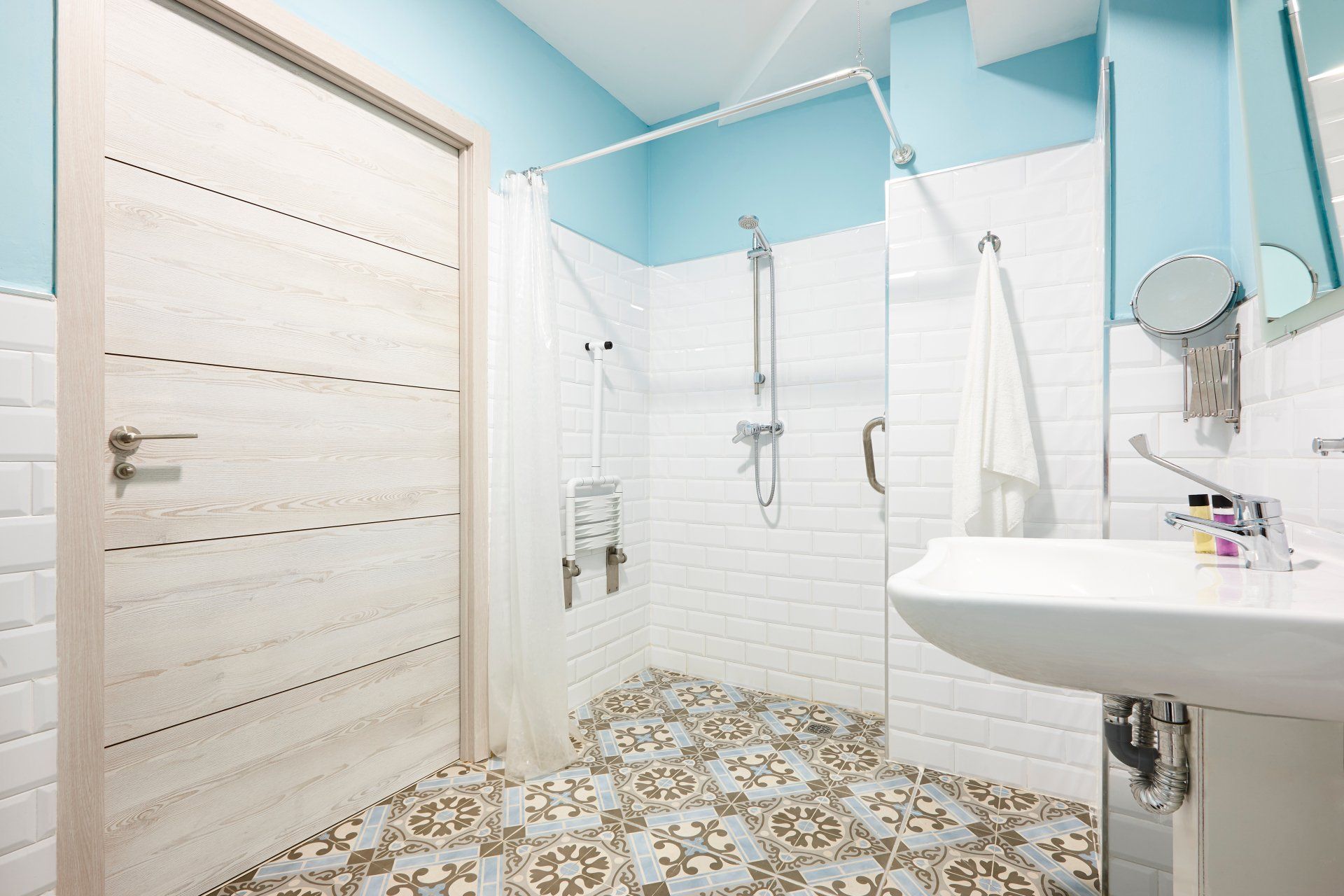 A bathroom with a walk in shower , sink and mirror.