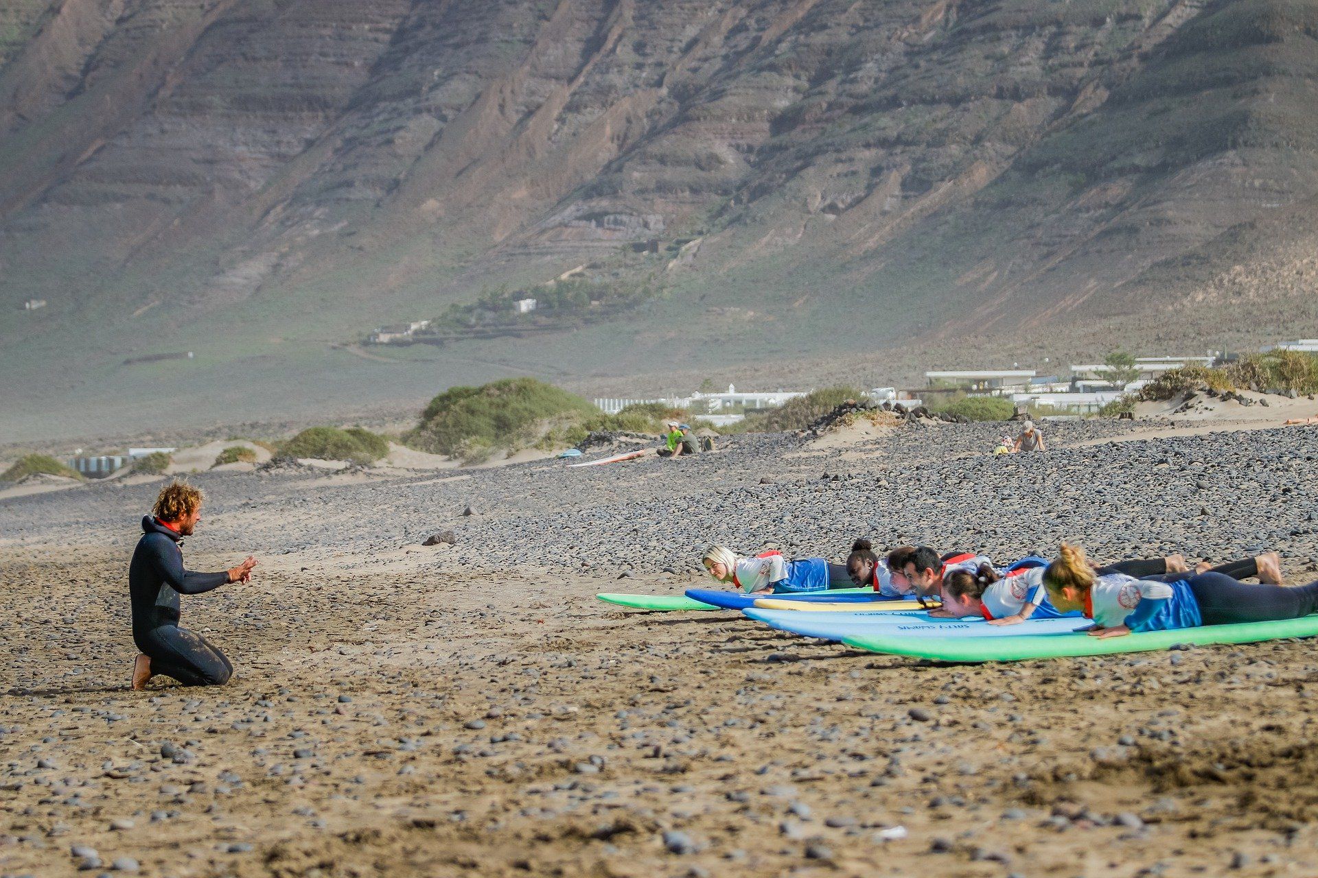 A group of people are sitting on surfboards on a beach, TAKING PHOTO.
