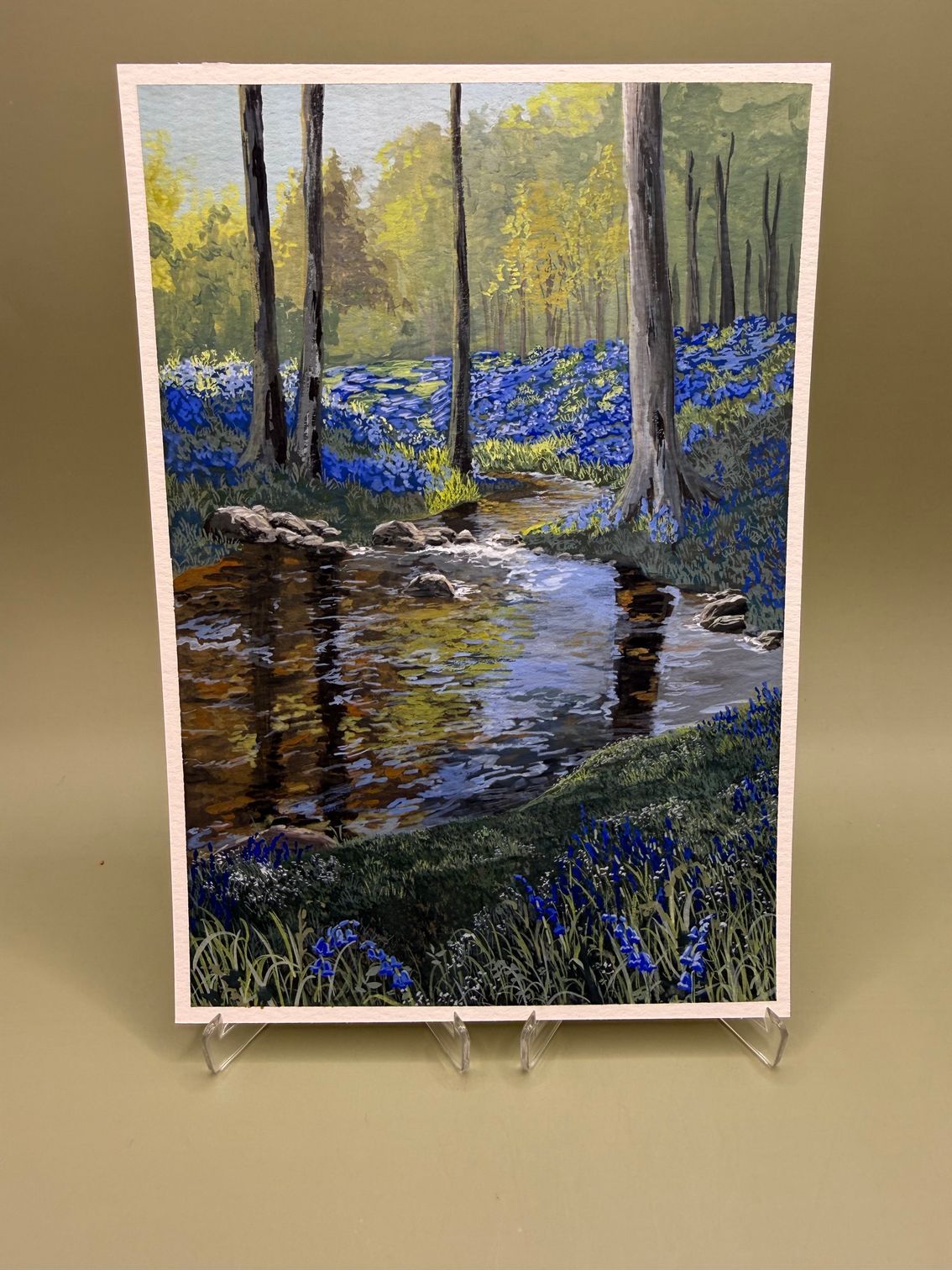 Impressionist painting of a forest stream with blue wildflowers and sunlight through tall trees.