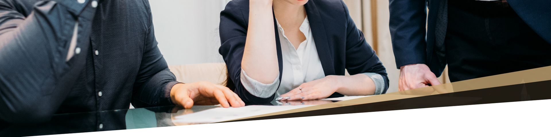 Three people in business attire sitting at a conference table in a meeting