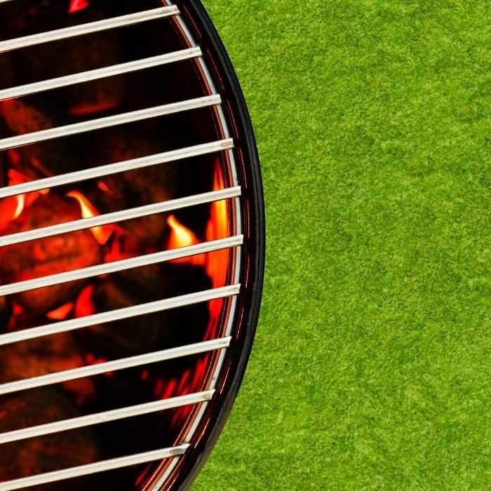 Close-up of a grill with glowing charcoal on green grass