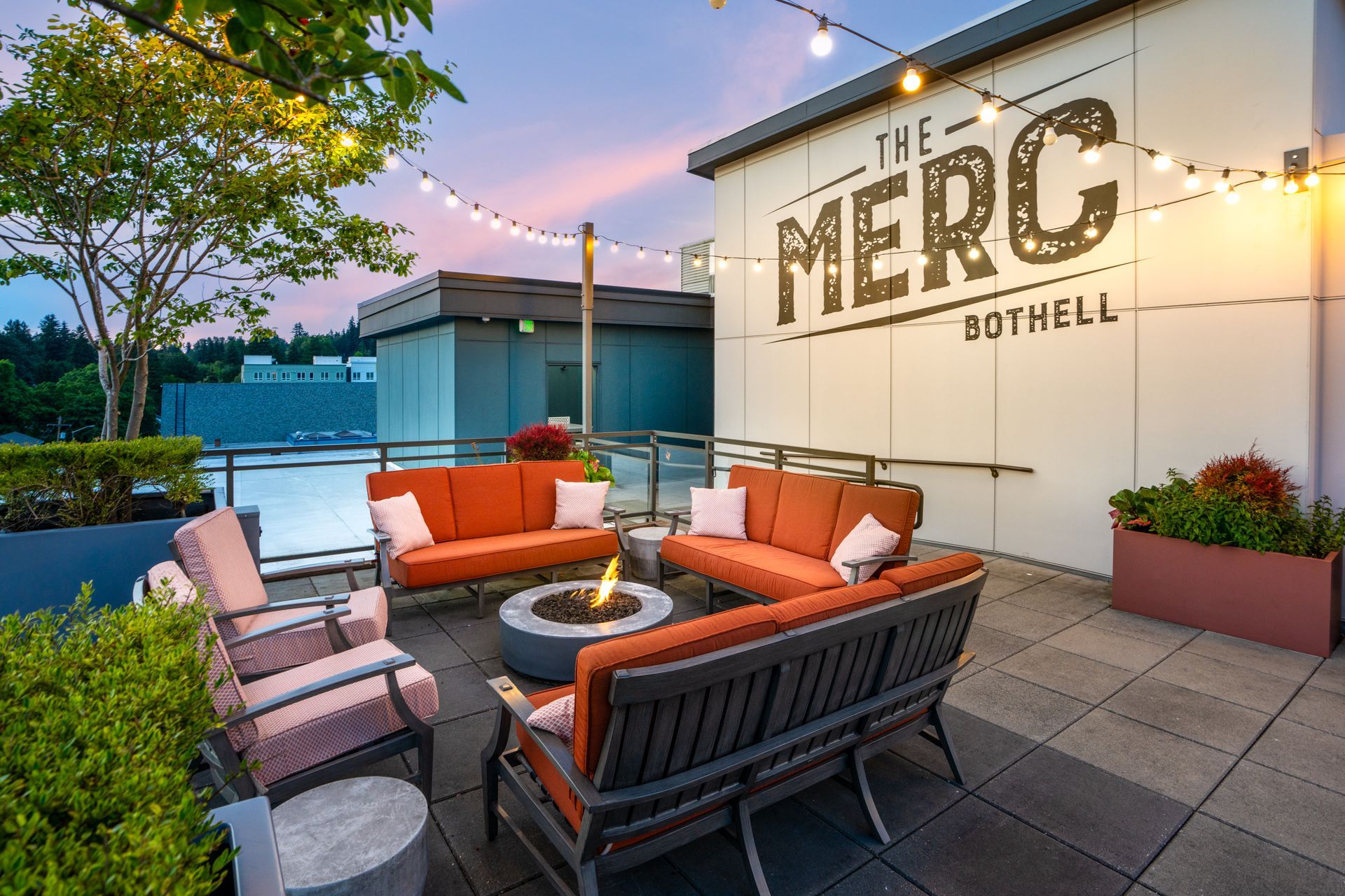 A patio with a fire pit and a couch in front of a building that says the merc